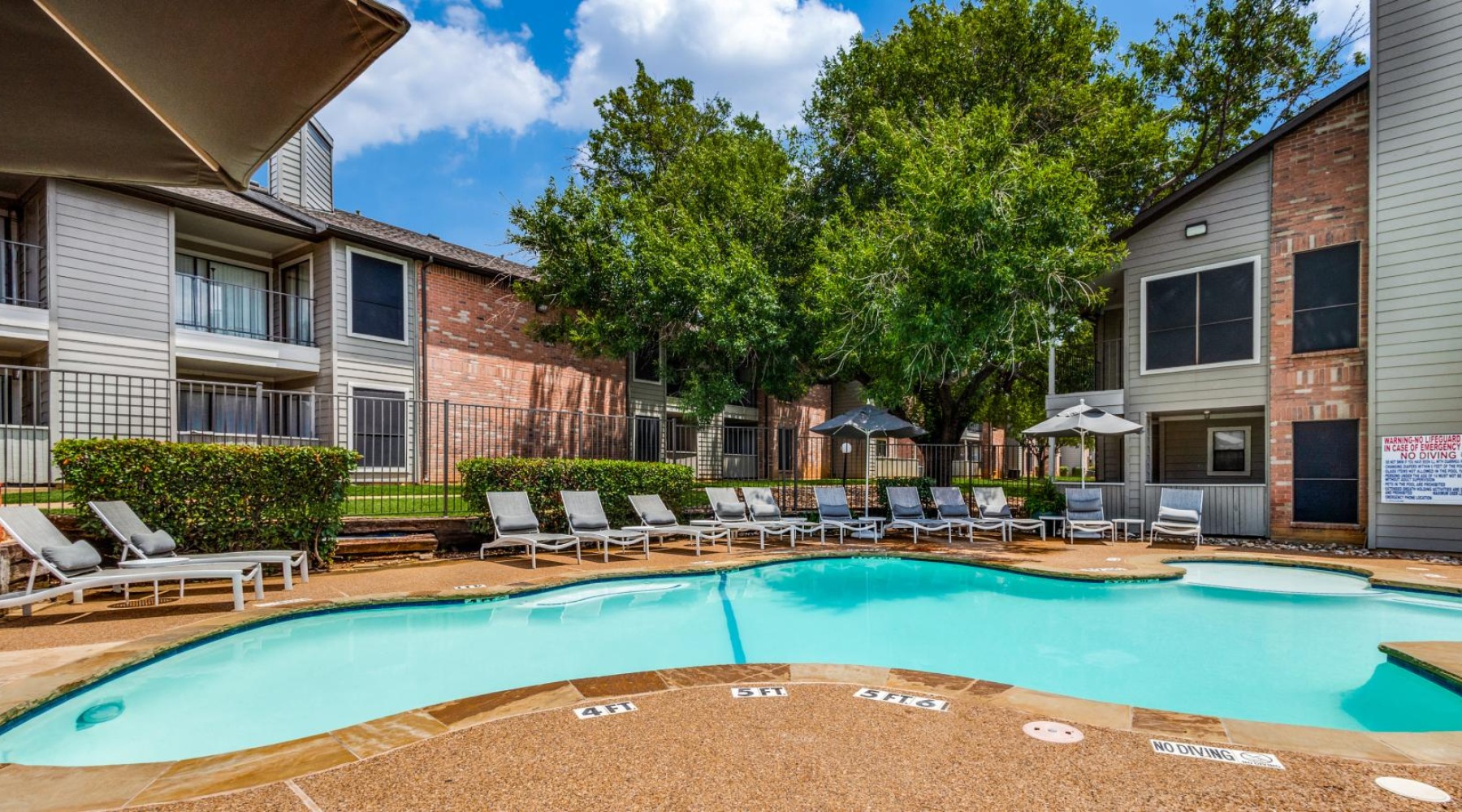 a swimming pool with chairs and umbrellas next to a building